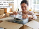 Emballer sa vaisselle : image ou photo d'une personne souriante emballe soigneusement des assiettes et des verres dans un carton de déménagement ouvert.