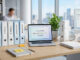 Archivage pro : image ou photo 'un bureau moderne et bien rangé avec des dossiers colorés, un ordinateur portable ouvert, quelques documents classés proprement.