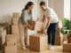 Cartons recyclés : image ou photo d'une famille ou un jeune couple en plein déménagement, entouré de cartons recyclés en kraft naturel. Certains cartons portent un petit symbole de recyclage.